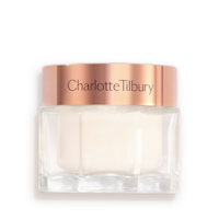 Pearly-white face cream in a glass jar with a gold-coloured lid with text on it, 'Charlotte's magic cream'.
